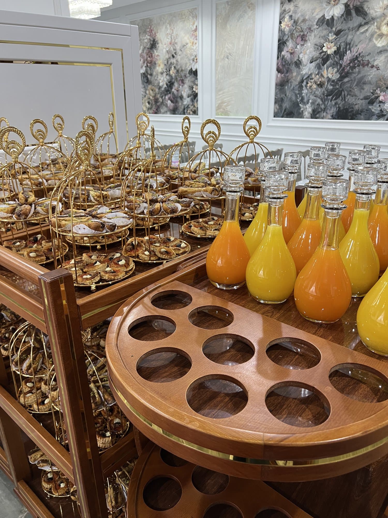 Des chariots de service dorés garnis de jus et de verres, prêts pour la réception.