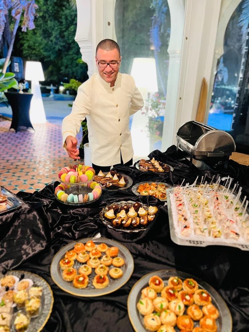 Un chef dispose les dernières pièces sur un buffet cocktail, en soirée.