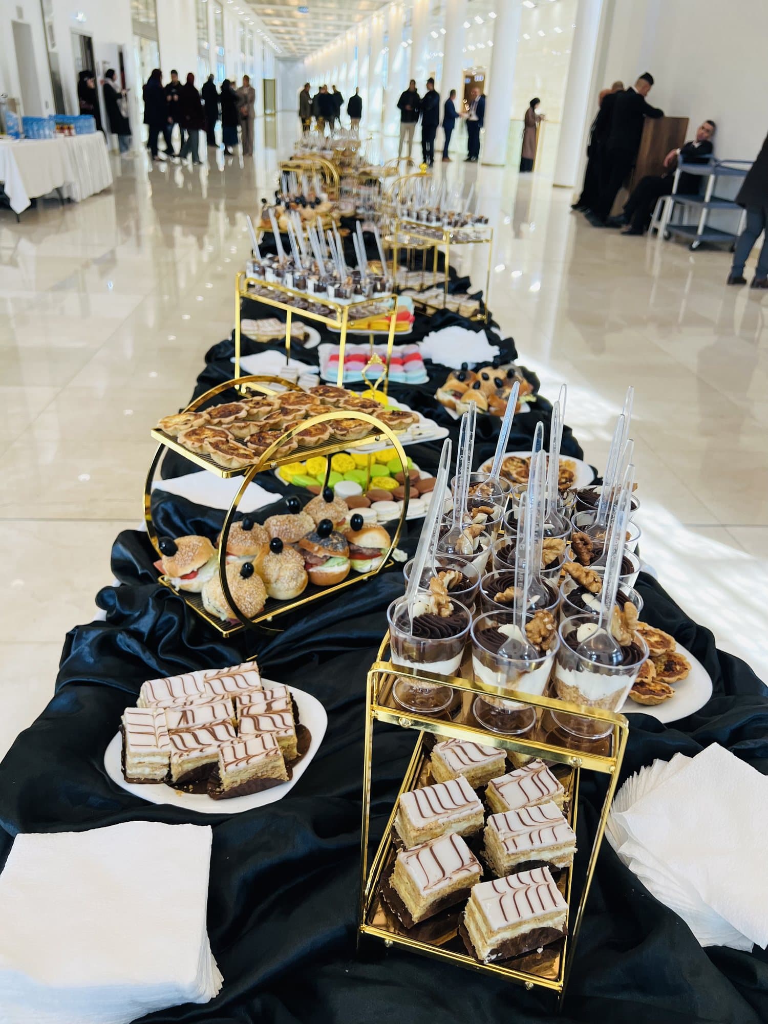 Un buffet de pause gourmande : verrines, mille-feuilles et petits gâteaux sur nappe noire.