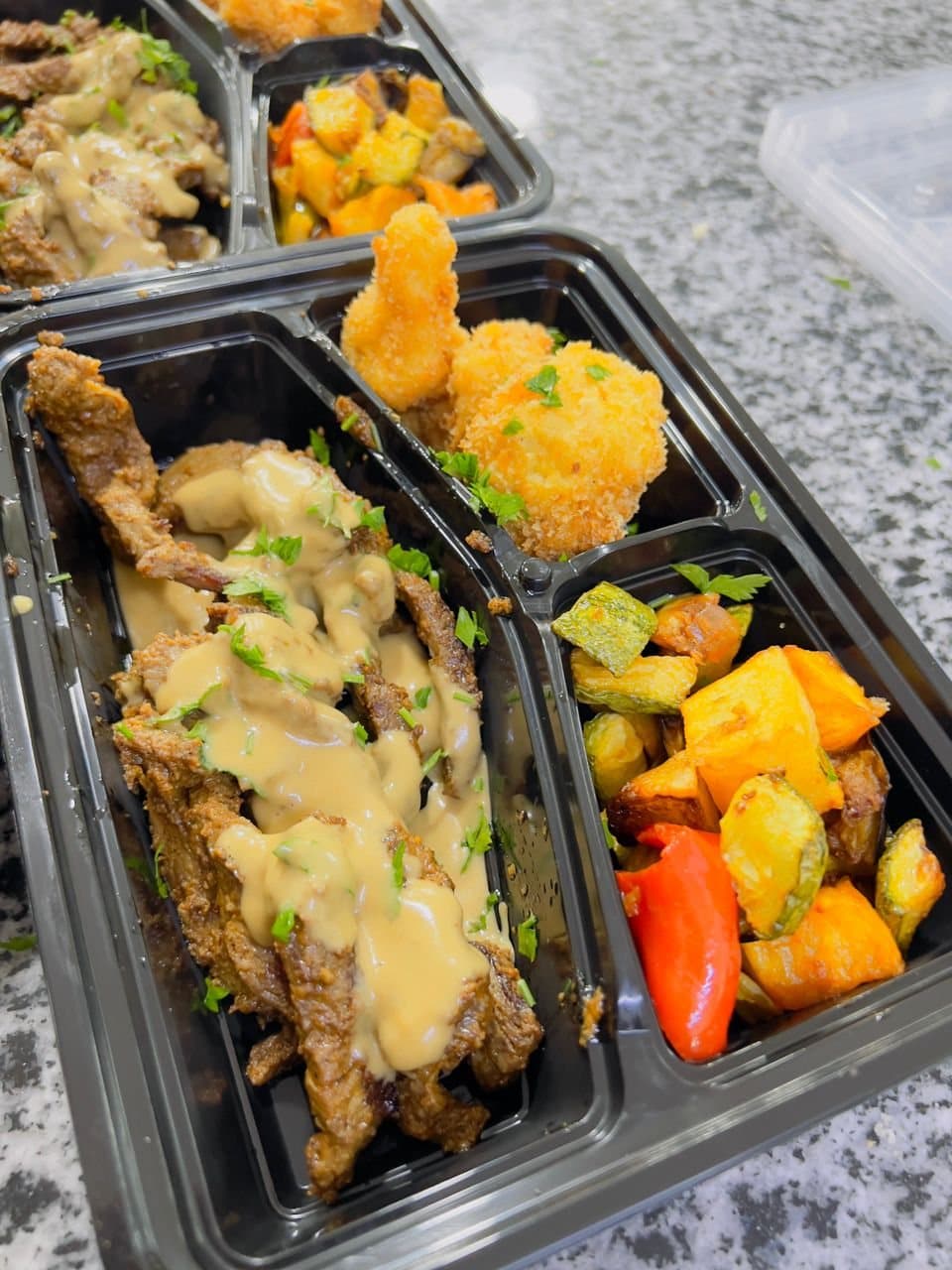 Un coffret repas : émincé de viande en sauce, croquettes et légumes grillés.