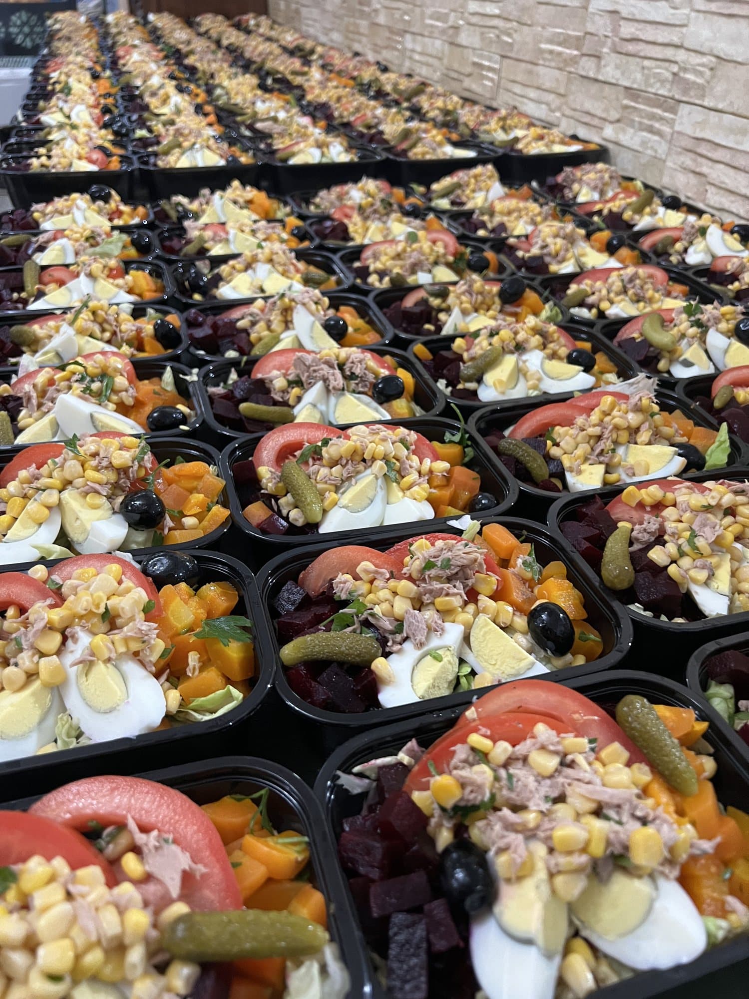 Des dizaines de coffrets de salade composée : œuf, thon, betterave, carotte et maïs.