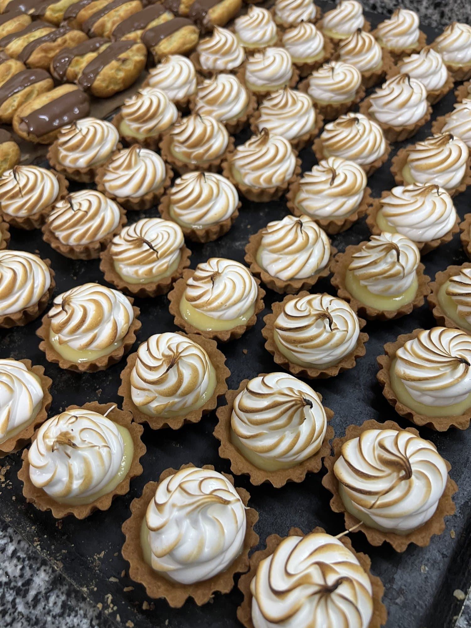 Des dizaines de tartelettes meringuées sur un plateau.